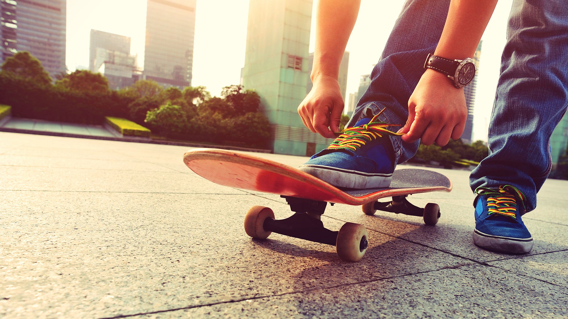 A boy tying a shoe lace on skateboard